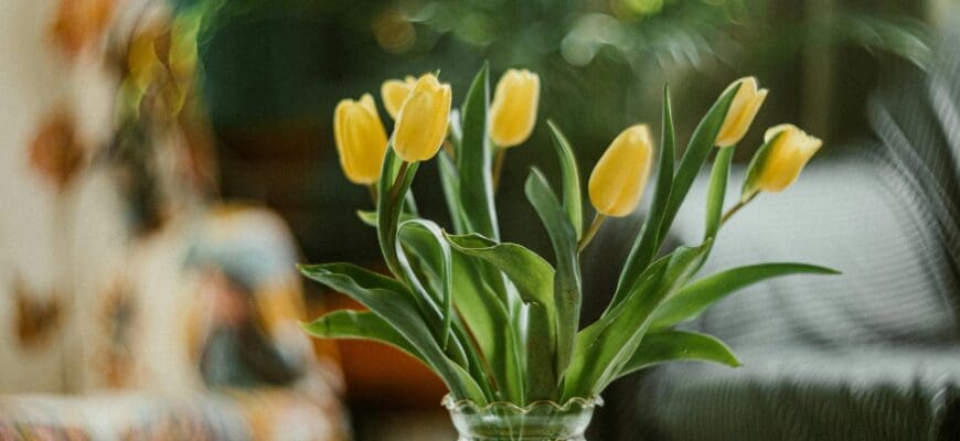 A living room table with a bouquet of yellow tulips in a vase